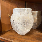 Tara Shaw 18th century Spanish pottery jar with a rustic, weathered patina and textured finish on a wooden shelf.