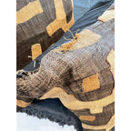Tara Shaw African Kuba pillow featuring handwoven geometric patterns in earthy brown and tan raffia with edge wear.