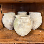 Tara Shaw set of four rustic 18th-century Spanish pottery jars with weathered patina on a wooden shelf.