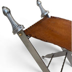 Tara Shaw pair of folding sword stools with argenté metal frames and brown leather seats in a campaign style.
