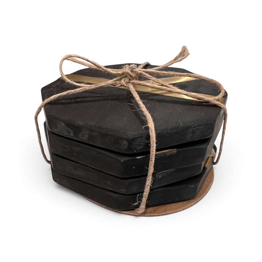 Tara Shaw black octagonal coaster set with gold accents tied together with rustic twine on a white background.