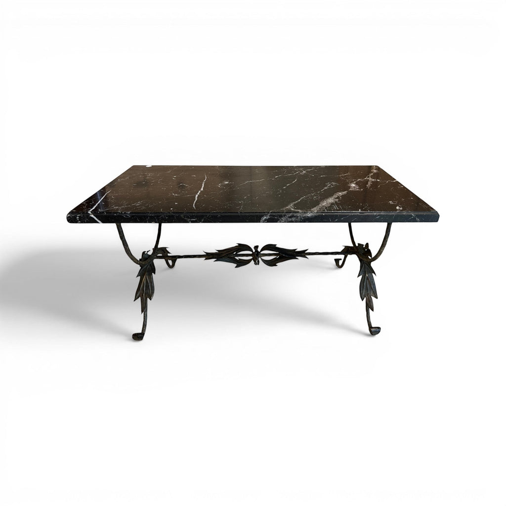 Tara Shaw coffee table with a polished black marble top and a sculptural bronze base featuring intricate leaf details.