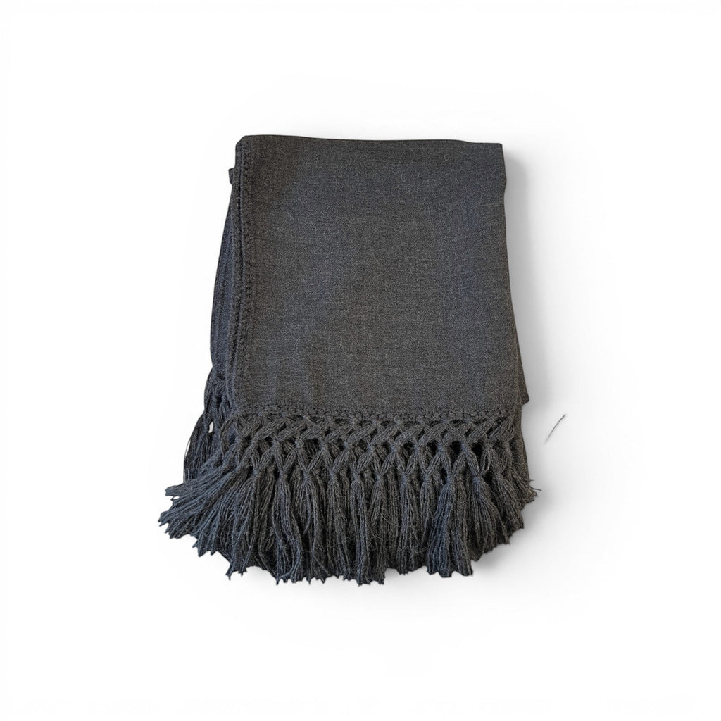 Tara Shaw dark grey alpaca bouclé throw blanket with decorative knotted fringe detail on a white background.