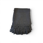 Tara Shaw dark grey alpaca bouclé throw blanket with decorative knotted fringe detail on a white background.