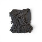 Tara Shaw dark grey alpaca bouclé throw blanket with a decorative knotted fringe edge on a white background.