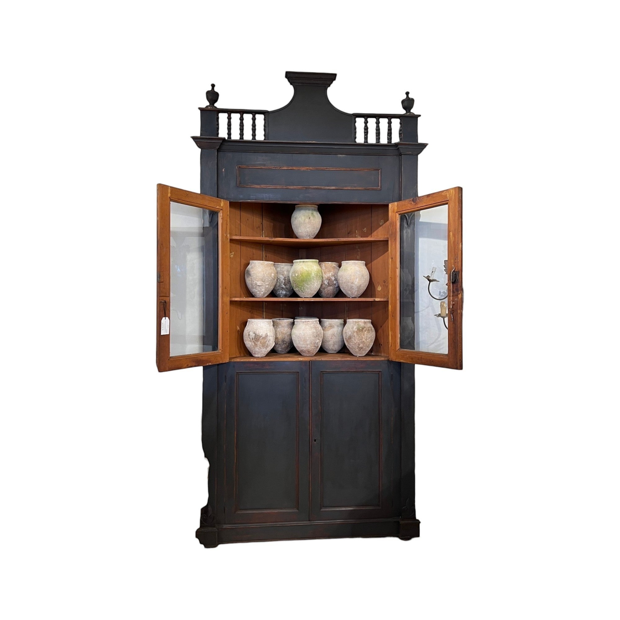 Tara Shaw 18th-century Italian ebonized corner cabinet with open glass doors and antique pottery on wooden shelves.