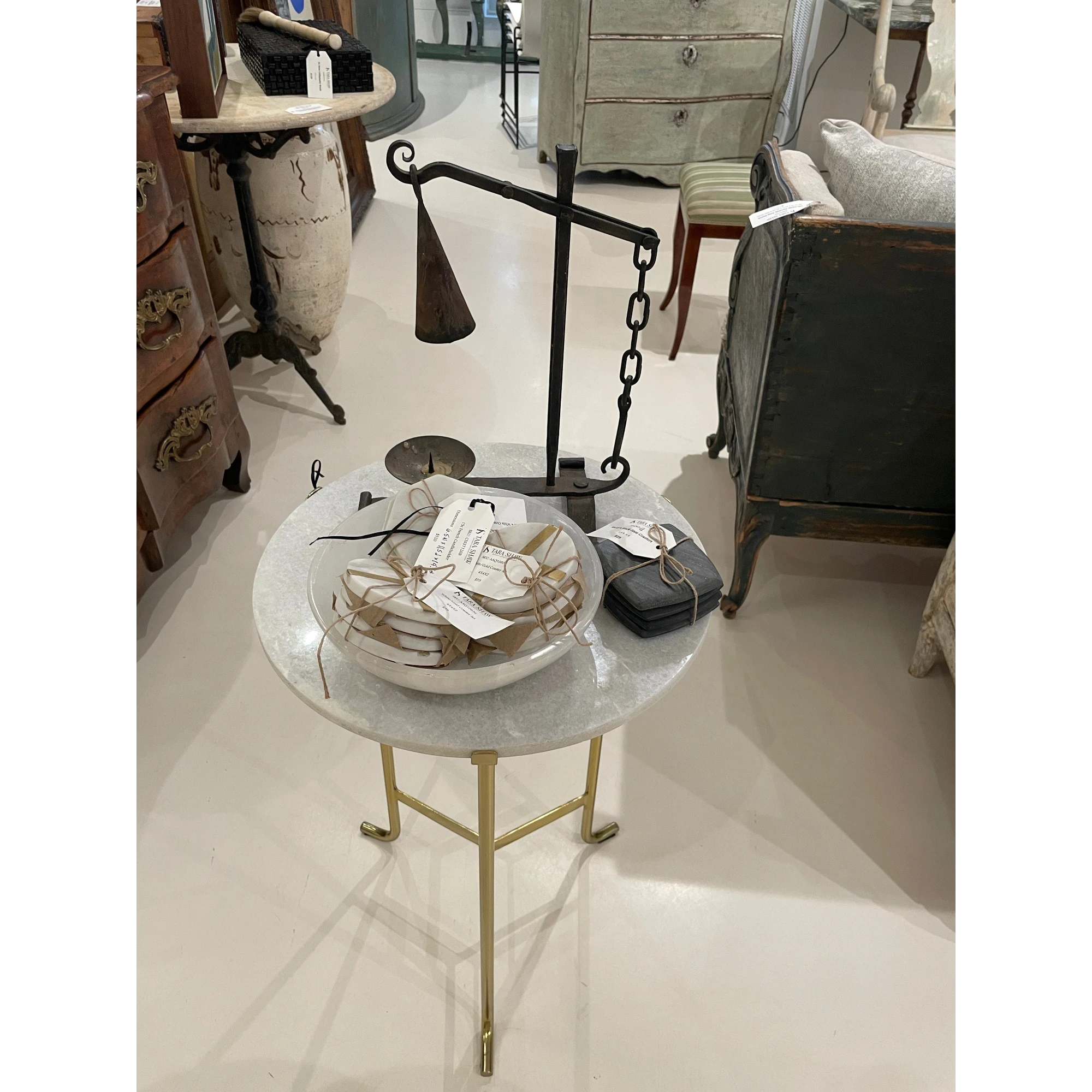 Tara Shaw 19th-century French candleholder with aged patina and metal chain detail on a marble-topped side table.