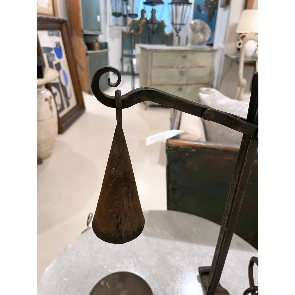 Tara Shaw 19th-century French iron candleholder with a conical shade and aged patina on a marble table.