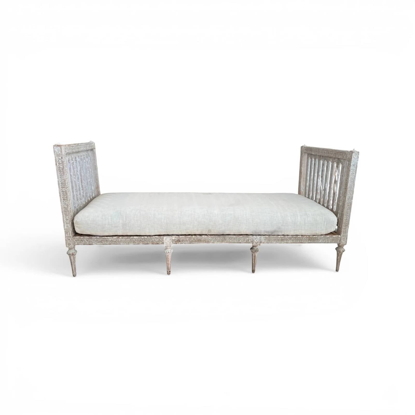Tara Shaw 18th century Gustavian daybed with carved wood frame, aged patina, and light linen upholstered cushion.