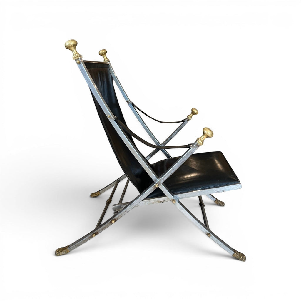 Tara Shaw vintage Maison Jansen folding chair with black leather seat and brass-toned metal frame, side view.
