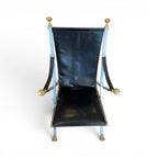 Tara Shaw vintage Maison Jansen folding chair with black leather seat and brass-toned metal frame details.