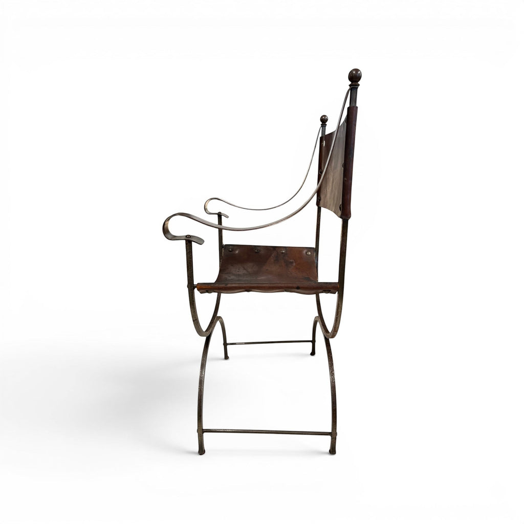 Tara Shaw early 20th century Savonarola chair with a sculptural metal frame and aged brown leather seat, side view.