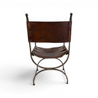 Tara Shaw early 20th century Savonarola chair with a sculptural metal frame and aged brown leather seat.