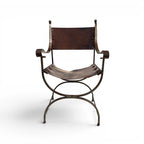 Tara Shaw early 20th century Savonarola chair with a sculptural metal frame and aged brown leather seat.