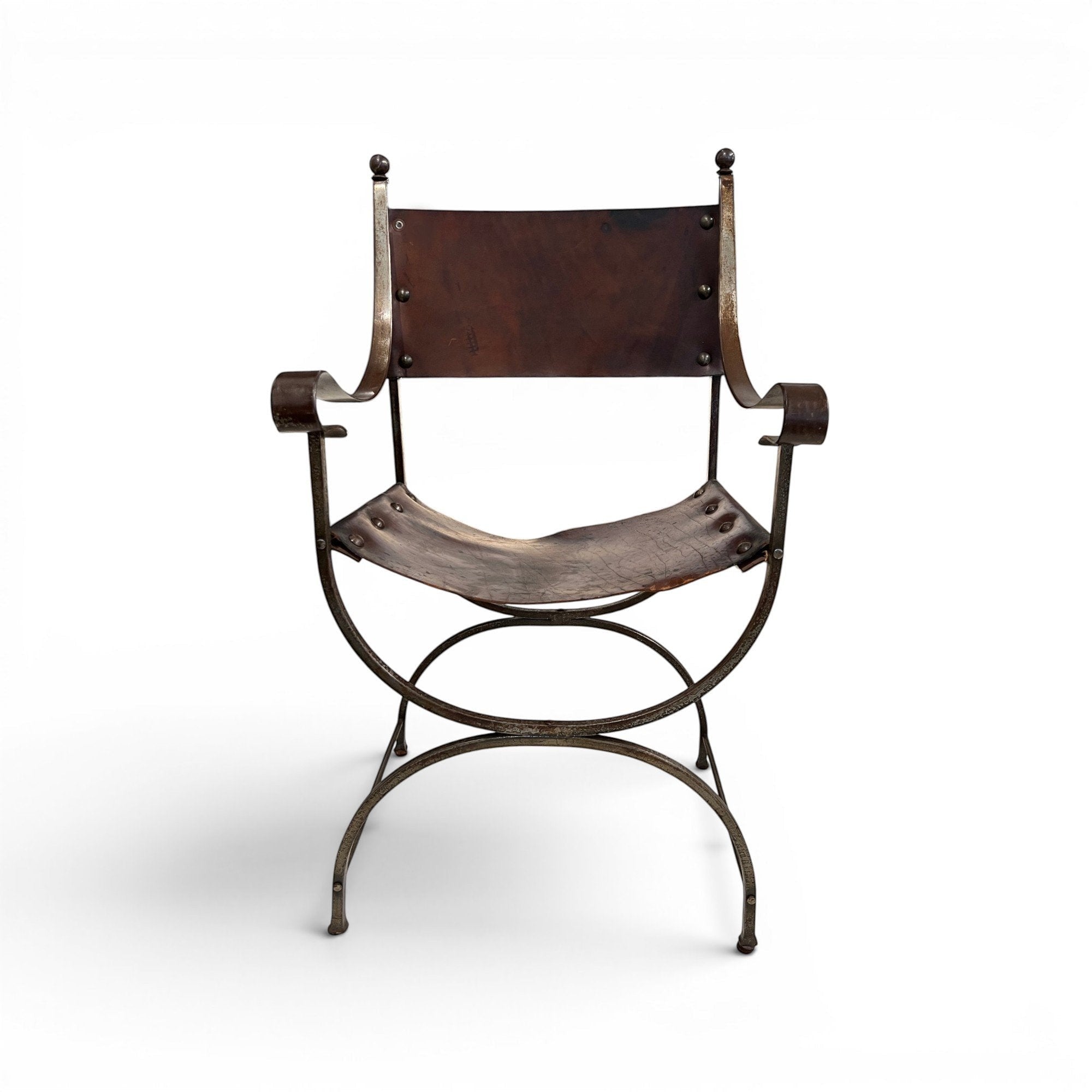 Tara Shaw early 20th century Savonarola chair with a sculptural metal frame and aged brown leather seat.