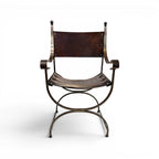 Tara Shaw early 20th century Savonarola chair with a sculptural metal frame and aged dark brown leather seat.
