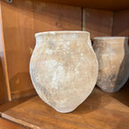 Tara Shaw rustic 18th century Spanish pottery jar with a weathered, textured patina on a wooden shelf.