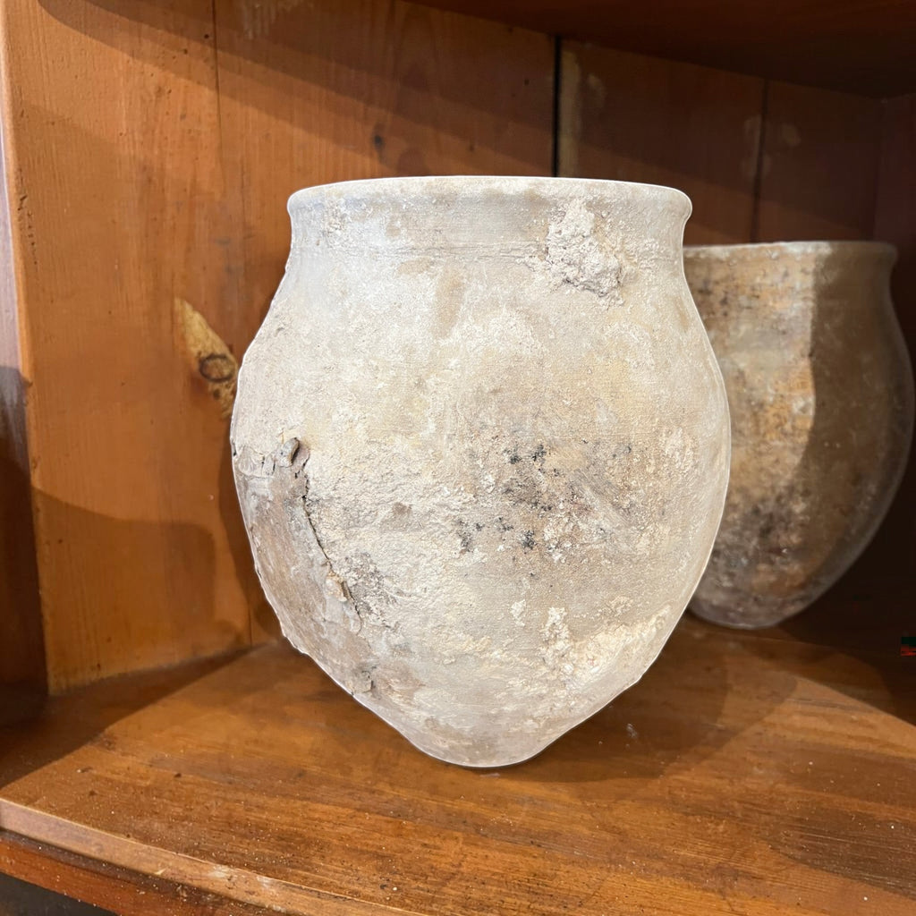 Tara Shaw 18th-century Spanish rustic pottery jar with a weathered, textured patina on a wooden shelf.