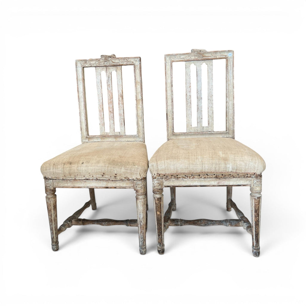 Tara Shaw pair of 18th-century Swedish chairs with distressed white paint, carved details, and natural linen seats.