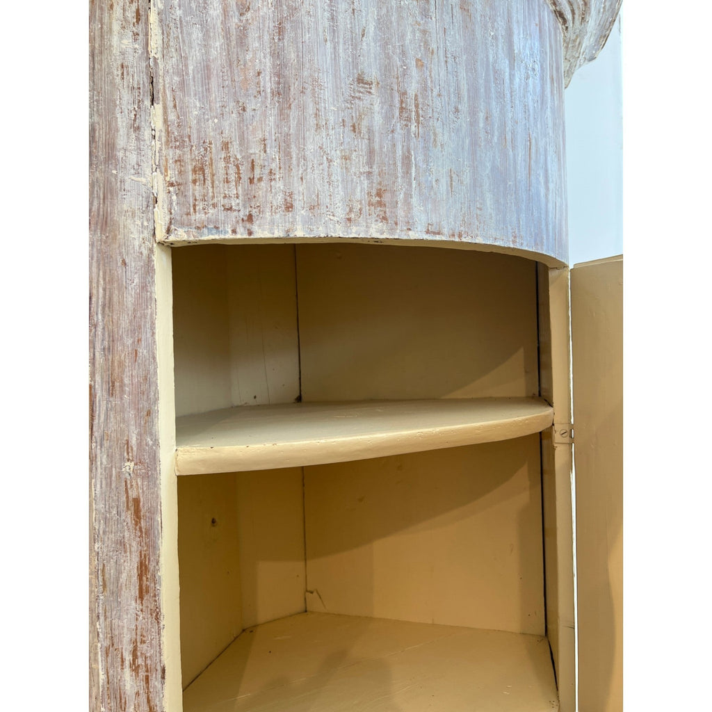 Tara Shaw 18th century Swedish Baroque corner cabinet with a distressed white finish and cream interior shelving.
